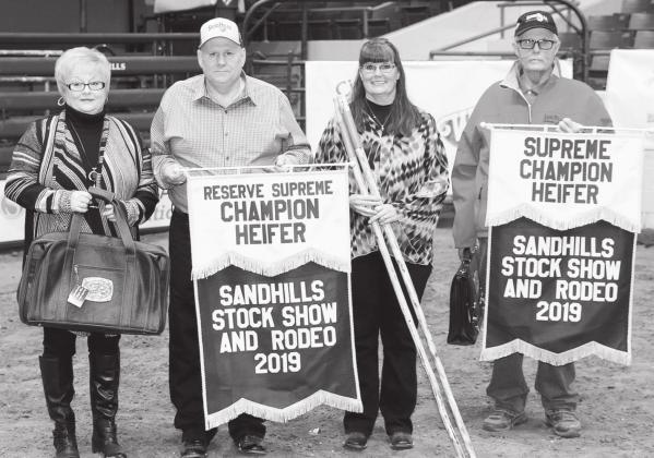 Dixie and Robert Cox, Jonama Myrick, and Morgan Cox, proudly display the champion banners they sponsored in memory of their patents Bob and Jo Jon Cox.