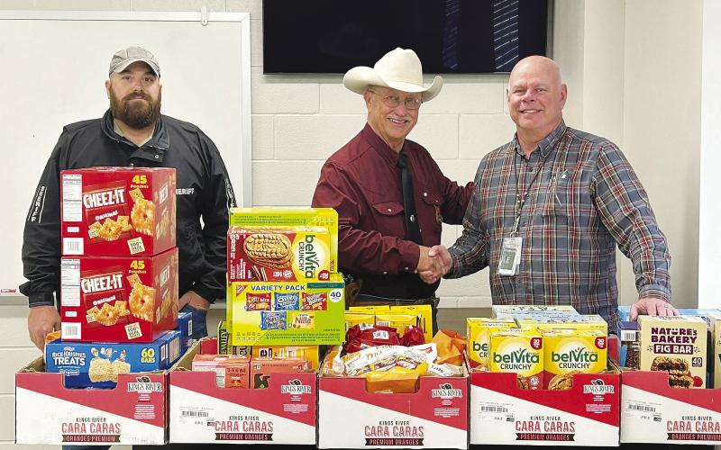 Martin County Sheriff’s Capt. and Emergency Management Director Chase Stiles (left), Sheriff Randy Cozart, and a representative from Diamondback Energy pose with boxes of snacks donated by the company to support the county’s emergency preparedness efforts. See story page one.