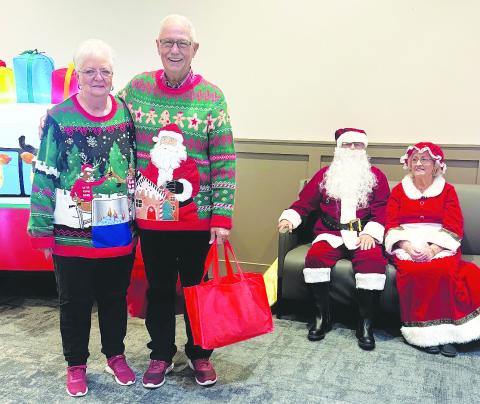 Danny and Billie Fryar pose next to Santa and Mrs. Claus at the senior center Christmas party. Each guest received a bag of gifts purchased with funds raised by The Corner Day Spa &amp; Salon.